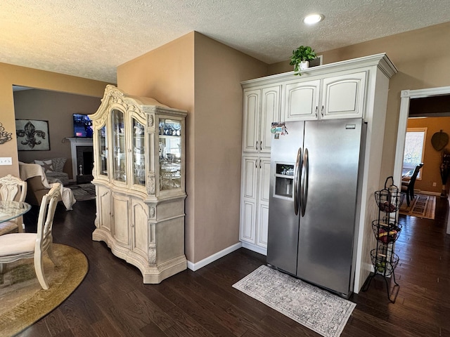 kitchen featuring a textured ceiling, white cabinetry, baseboards, dark wood-style flooring, and stainless steel fridge