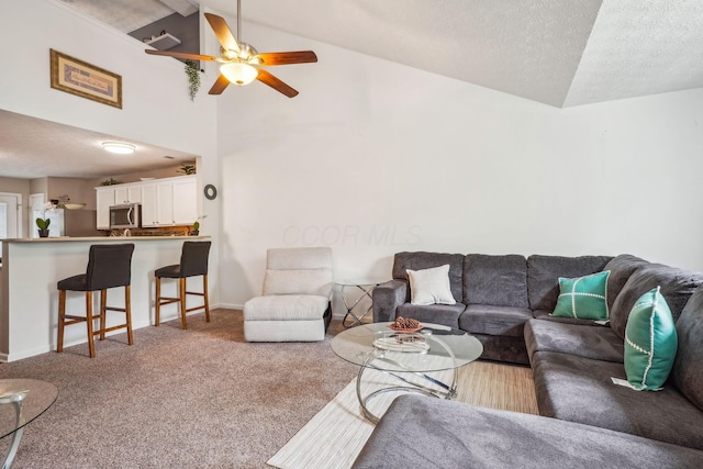 carpeted living room with a ceiling fan, vaulted ceiling, a textured ceiling, and baseboards