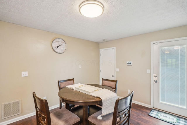 dining area featuring baseboards, visible vents, a textured ceiling, and dark wood-style flooring