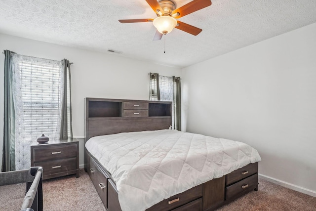 carpeted bedroom with a textured ceiling, visible vents, ceiling fan, and baseboards