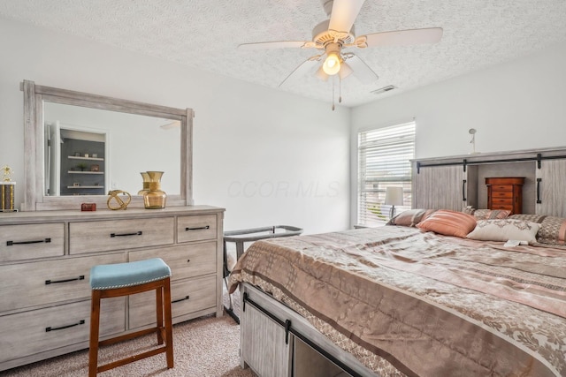 bedroom featuring visible vents, a ceiling fan, a textured ceiling, and light colored carpet