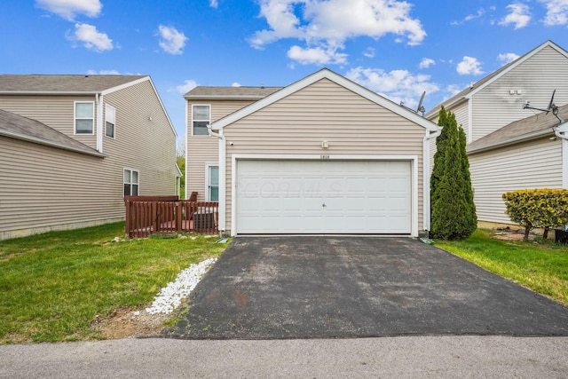 view of front of house featuring a front lawn, driveway, a garage, and fence