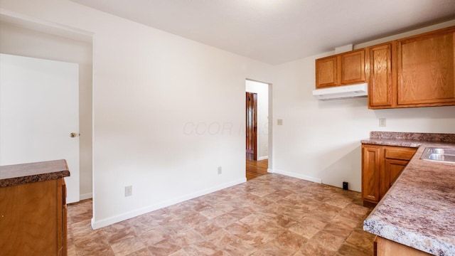 kitchen featuring brown cabinets, a wall mounted air conditioner, and baseboards