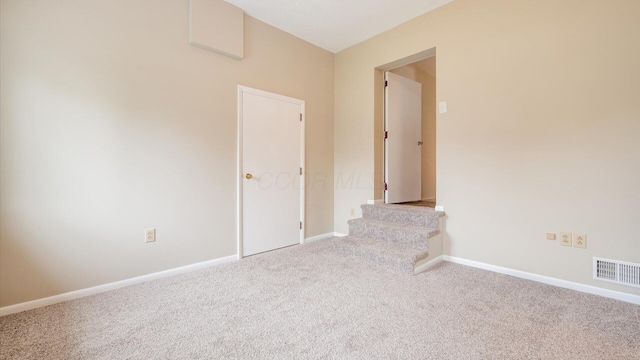 carpeted spare room featuring stairs, visible vents, and baseboards