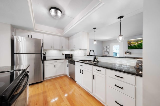 kitchen with a sink, white cabinets, a tray ceiling, and black appliances