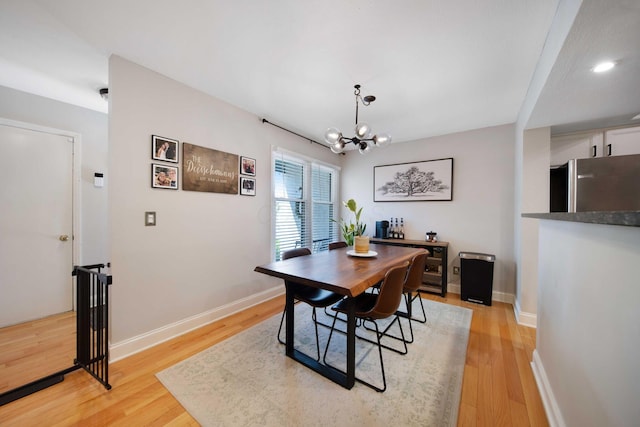 dining space featuring light wood-style floors, baseboards, and a chandelier