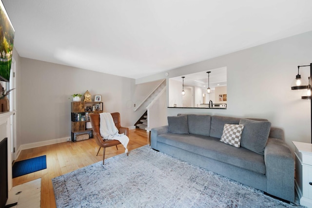 living area with light wood-style floors, baseboards, and stairway
