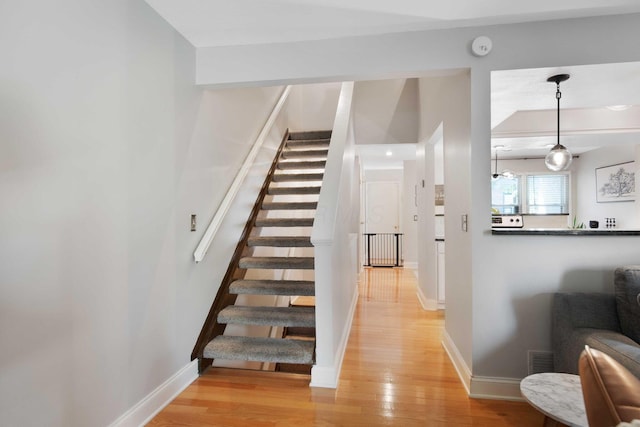 stairway with baseboards, visible vents, and wood finished floors