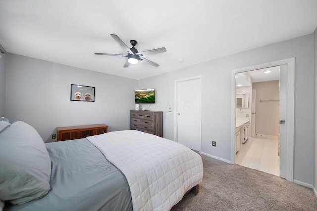 bedroom featuring a ceiling fan, baseboards, light carpet, and ensuite bathroom