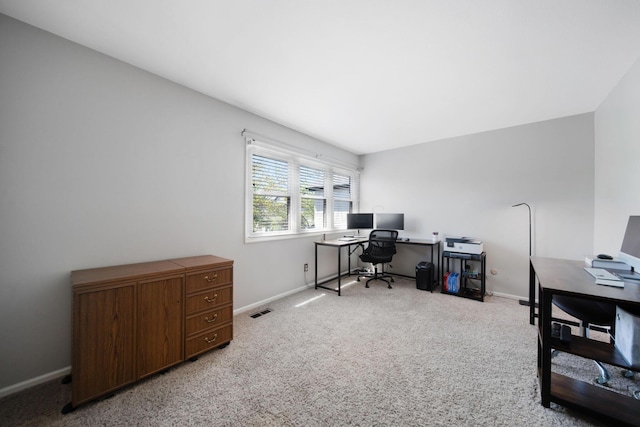 office space featuring baseboards, visible vents, and light carpet