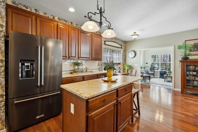 6767 Burnside Ln, Dublin, OH 43016 - kitchen with tasteful backsplash, light stone counters, high quality fridge, a center island, and dark wood-type flooring