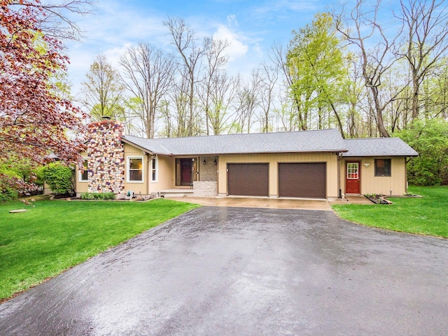 view of front facade with a garage, a chimney, driveway, and a front yard