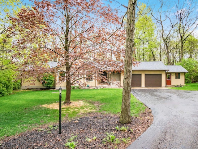 view of front facade with an attached garage, driveway, roof with shingles, and a front lawn