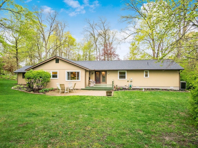 rear view of house with a patio, a lawn, roof with shingles, and cooling unit