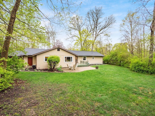 rear view of property with a yard, a patio, and roof with shingles