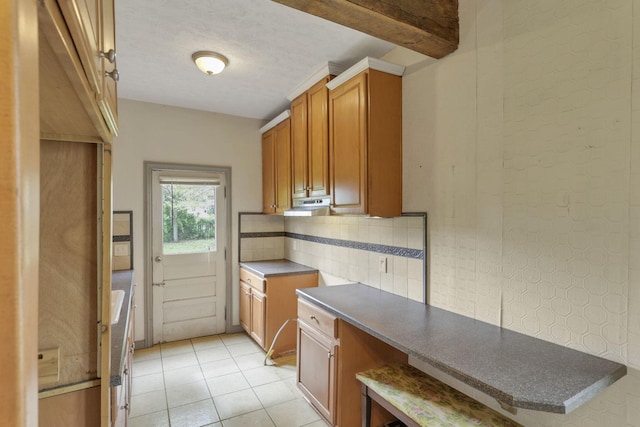 423 Hudson Ave, Newark, OH 43055 - kitchen featuring light tile patterned flooring, dark countertops, brown cabinetry, and under cabinet range hood