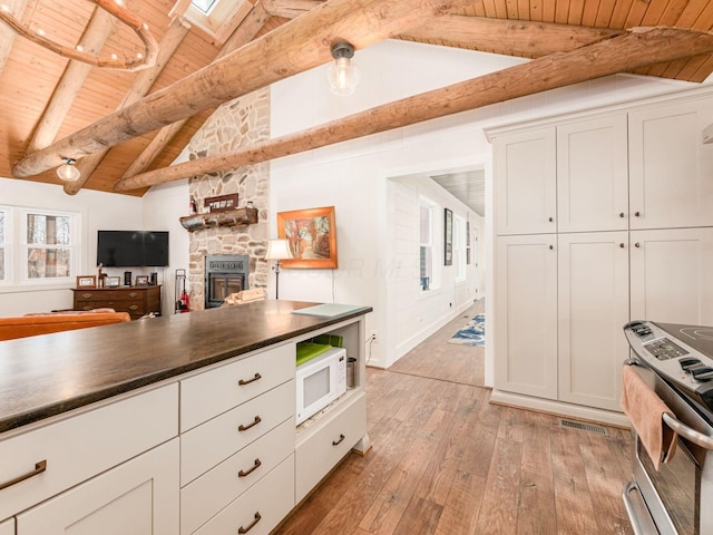 kitchen with wood ceiling, white microwave, light wood-type flooring, and stainless steel electric range oven