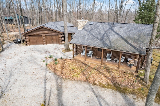 view of front of home featuring a porch, a chimney, log siding, a garage, and a shingled roof
