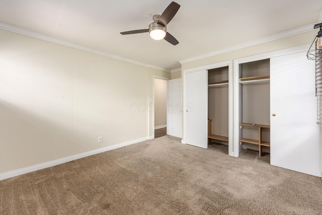 unfurnished bedroom featuring ceiling fan, crown molding, baseboards, multiple closets, and carpet