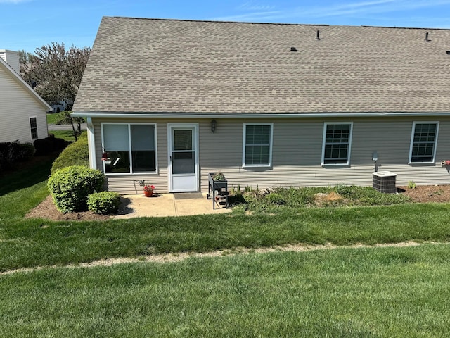 back of house with a lawn, a shingled roof, and central air condition unit