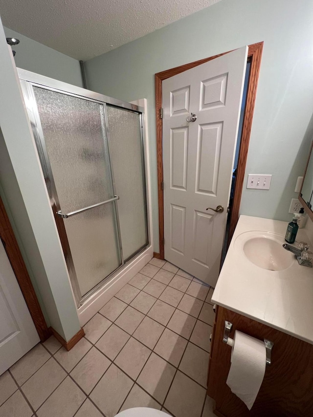 full bathroom with vanity, tile patterned flooring, a stall shower, and a textured ceiling