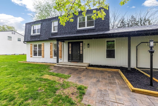 view of front of house with roof with shingles, covered porch, mansard roof, and a front lawn