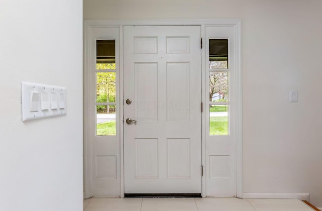 doorway with baseboards and light tile patterned flooring