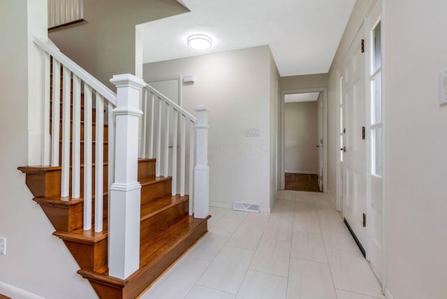 interior space with stairway, light tile patterned floors, baseboards, and visible vents