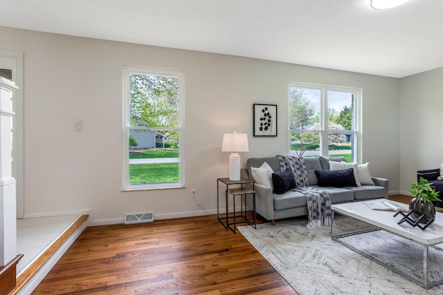 living area featuring baseboards, wood finished floors, and visible vents