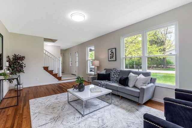 living room featuring stairway, baseboards, wood finished floors, and a healthy amount of sunlight