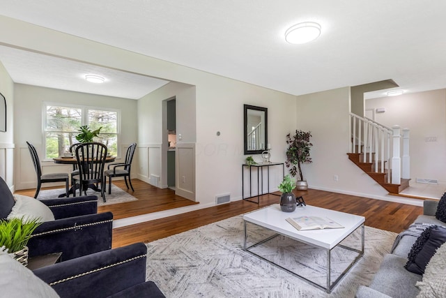living area with stairway, wood finished floors, and visible vents