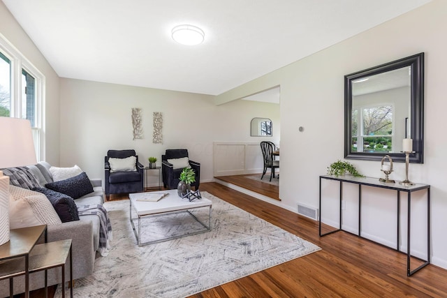 living room featuring visible vents, baseboards, and wood finished floors