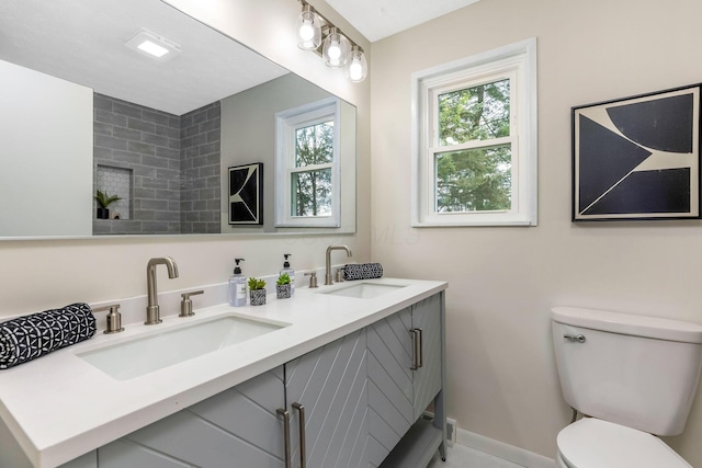 full bathroom with double vanity, a sink, baseboards, and toilet