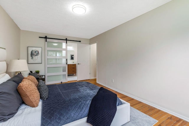 bedroom featuring baseboards, a barn door, and light wood-type flooring