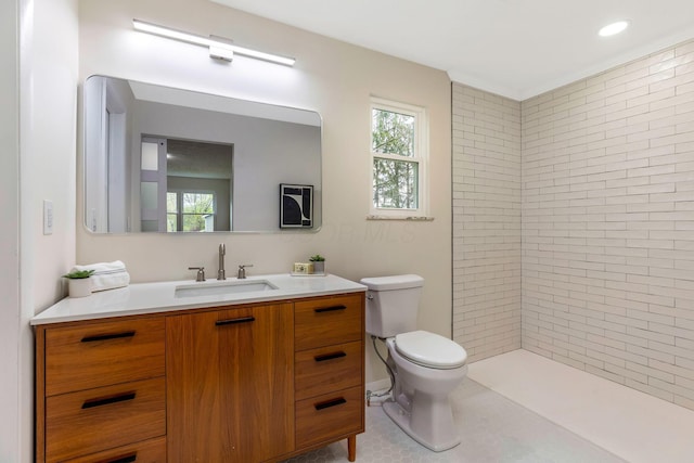 full bath with vanity, a tile shower, a healthy amount of sunlight, and toilet