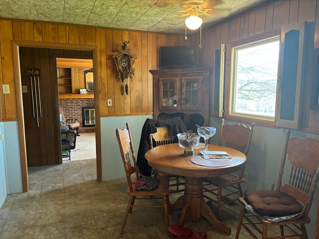 5398 Marietta Rd SE, New Lexington, OH 43764 - dining space featuring wooden walls, a ceiling fan, and a brick fireplace