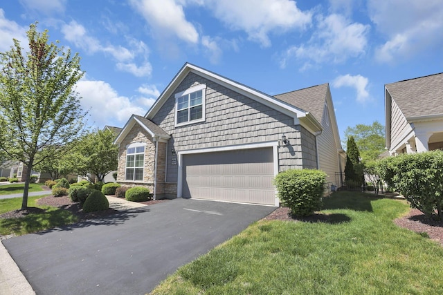 view of front of home featuring driveway, a front lawn, roof with shingles, and a garage