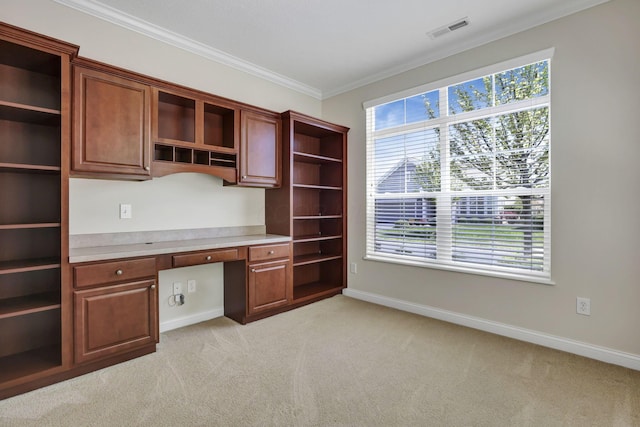 unfurnished office with visible vents, ornamental molding, built in study area, baseboards, and light colored carpet