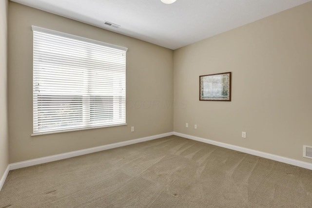 empty room featuring light colored carpet, baseboards, and visible vents