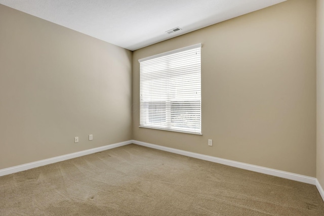 unfurnished room with visible vents, baseboards, and light colored carpet