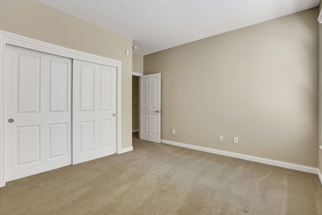 unfurnished bedroom with baseboards, carpet, and a closet