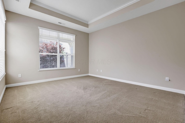 carpeted empty room with crown molding, baseboards, a tray ceiling, and visible vents