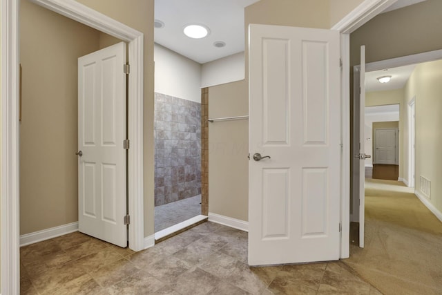 bathroom featuring baseboards, visible vents, and a tile shower