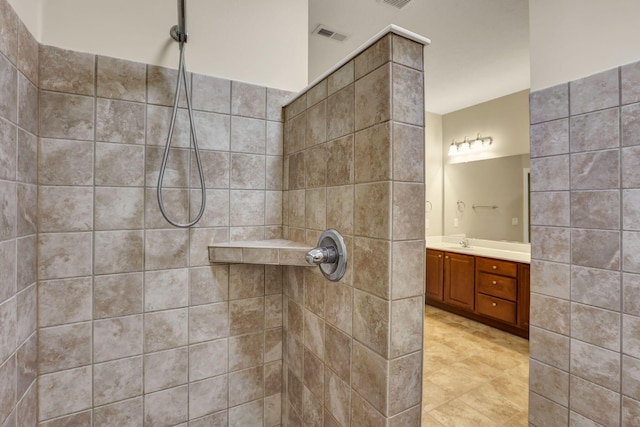 bathroom with vanity, a tile shower, and visible vents