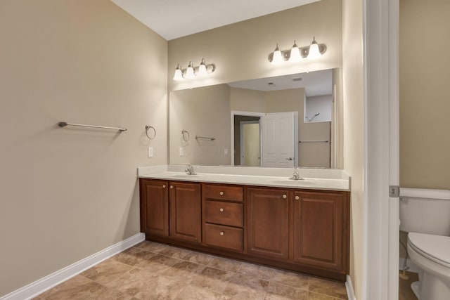 bathroom featuring a sink, baseboards, toilet, and double vanity