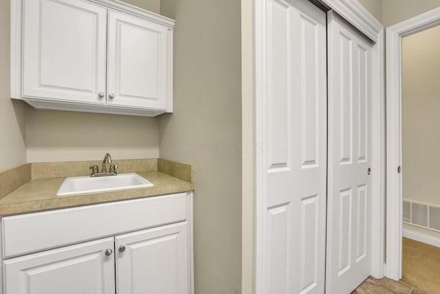 clothes washing area with a sink and visible vents