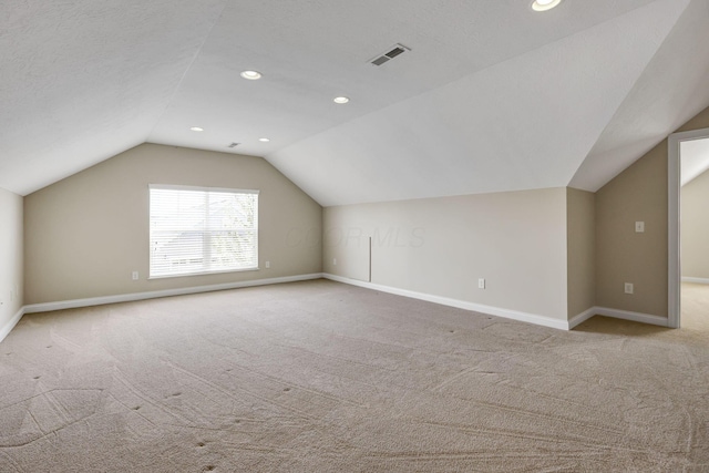 additional living space featuring carpet flooring, baseboards, visible vents, and lofted ceiling