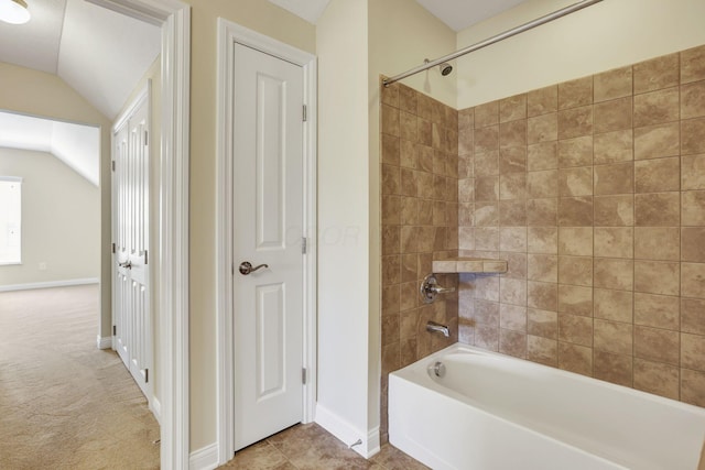 bathroom featuring baseboards, shower / bathing tub combination, and vaulted ceiling