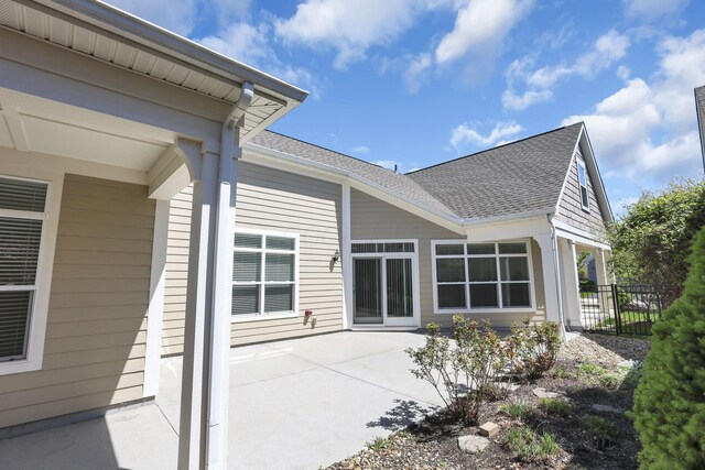rear view of property featuring fence, a shingled roof, and a patio area