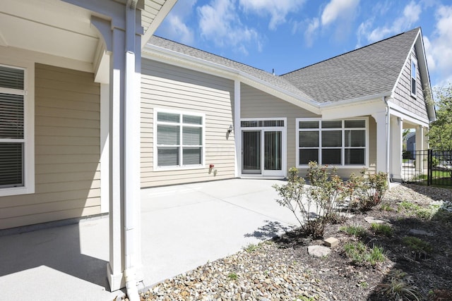 rear view of property featuring roof with shingles, fence, and a patio